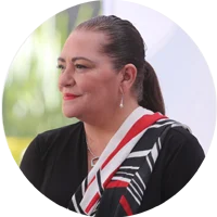 Woman with pulled-back hair wearing black top with red and white striped collar detail